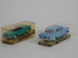 two toy cars in a clear box on a white surface