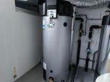 a water heater in the corner of a room next to a toilet