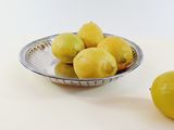 a bowl of lemons on a table next to a bowl of lemons