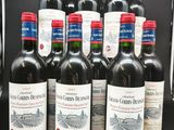 six bouteilles de vin rouge sont alignées sur une table noire