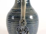 a blue vase with a rose on it on a white surface