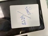 a tablet computer with a note on it sitting on a glass table