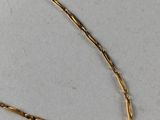 a close up of a gold necklace on a white surface