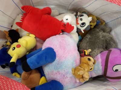 a lot of stuffed animals in a bag on the bed