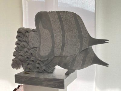 une statue représentant un poisson, posée sur un socle dans une pièce