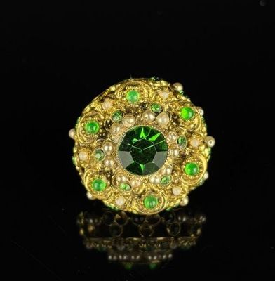 Broche en métal doré à décor filigrané, ornée de pierres ver…