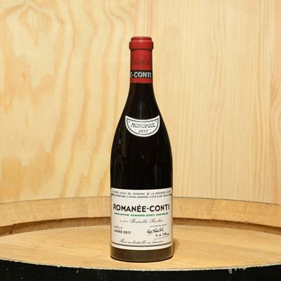 a bottle of wine sitting on top of a barrel