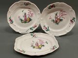three plates with flowers and fruit painted on them sit on a table