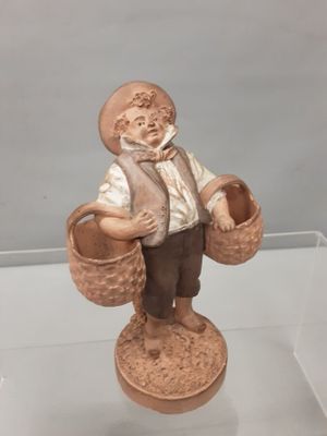 une figurine représentant un homme portant des paniers, posée sur un socle