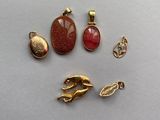 trois breloques dorées et un pendentif en forme de patte de chat