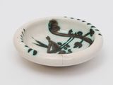 a small bowl with a bird on it on a white surface
