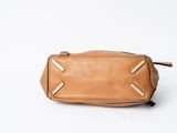 the small tan leather bag is on a white surface