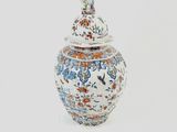 a white and blue vase with a lid on a white surface