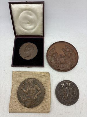 trois médailles de bronze dans une boîte avec un sac en tissu