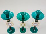 three green glass candlesticks sitting on a white table