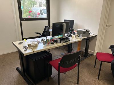 un bureau avec deux ordinateurs et une chaise devant une fenêtre