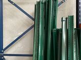 a rack of green metal pipes in a warehouse