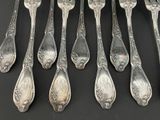 six silver spoons with ornate designs are lined up on a black surface