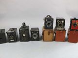 several old cameras are lined up in a row on a white surface