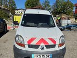 une camionnette blanche garée sur un parking, avec une bande rouge et blanche à l'avant