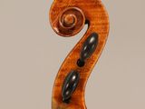 a close up of a violin neck with a fiddle in the background