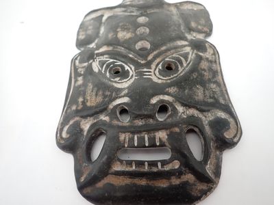 un masque noir posé sur une table blanche, sur fond blanc