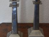 two metal candles that are on a wooden table