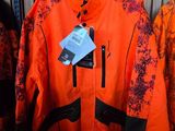 une veste orange et noire accrochée à un portant dans un magasin