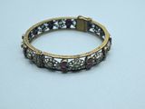 a close up of a gold bracelet with purple stones on a white surface