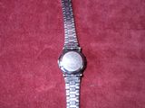 wrist watch laying on a red carpeted surface with a red background
