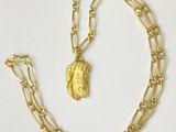 a close up of a gold chain with a coin on it