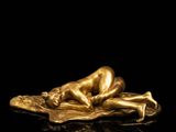 a gold figurine of a woman laying on a leaf