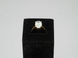 a gold ring with a white diamond on top of a black velvet ring stand