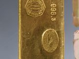 a gold bar next to a small doll holding a gold bar
