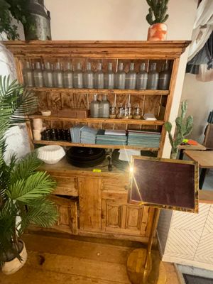 une armoire en bois surmontée d'un miroir, avec une plante en pot dans un coin de la pièce