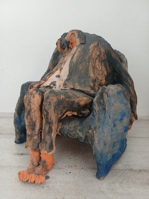 une sculpture représentant un homme assis sur une chaise