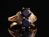 gros plan d'une bague en or avec un saphir et des diamants