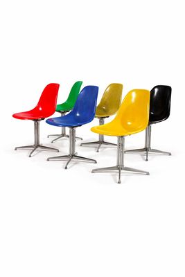 quatre chaises de couleurs différentes alignées sur une surface blanche