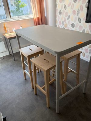 une petite table avec deux tabourets devant une fenêtre