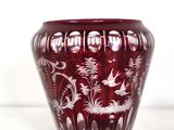 a red vase with white designs on it on a white surface