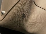 beige leather handbag with rivets and rivets sitting on a table
