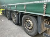 un semi-remorque vert avec un pneu crevé, garé sur le bord de la route