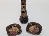 two small vases and a small bowl are sitting on a white surface