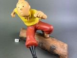 figurine of a man sitting on a log on a gray surface
