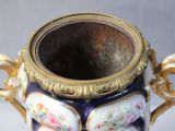 a vase with a handle that has flowers painted on it