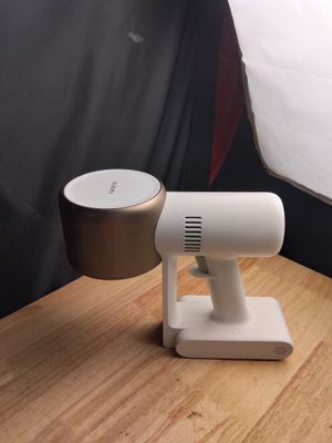 un petit objet blanc posé sur une table en bois, à côté d'une lampe