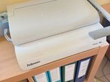 a printer sitting on top of a desk next to a book shelf