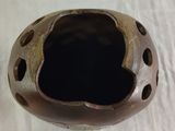 a brown vase with holes in it sitting on a table