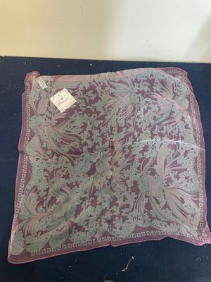 a close up of a pink and white square scarf on a table