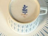 une tasse et une soucoupe posées sur une assiette sur laquelle est inscrit un nom